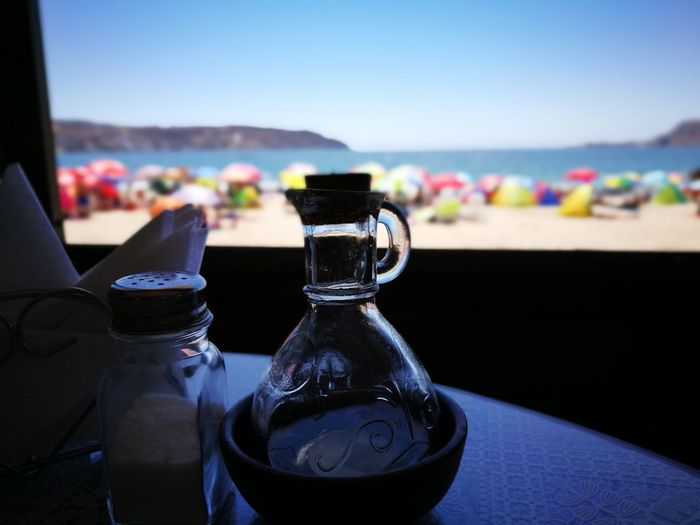 Close-up of salt shaker and jar on table at beach