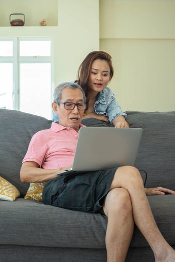 Young woman using mobile phone while sitting on sofa