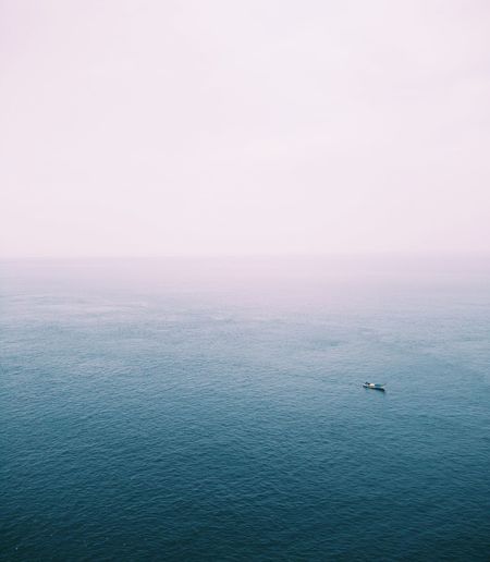 Take a photo of a boat in the middle of a blue ocean