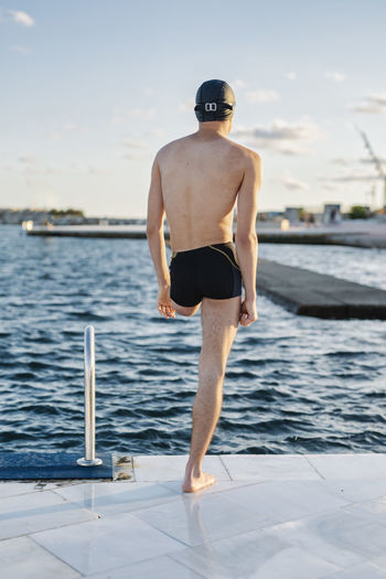 Rear view of shirtless man standing in swimming pool