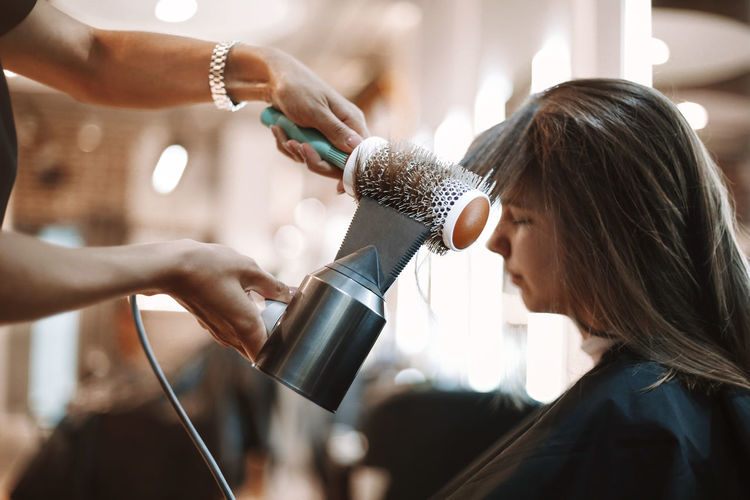 Hairdresser drying hair of customer at salon