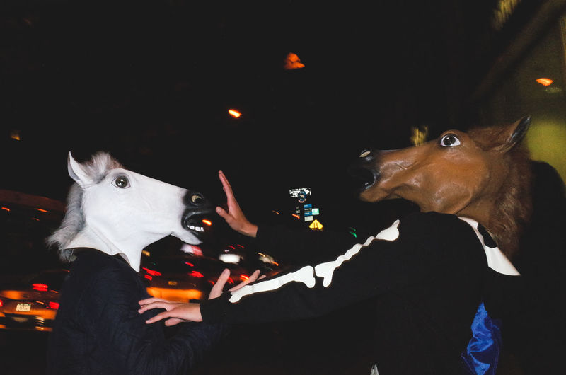 People wearing horse masks in darkroom