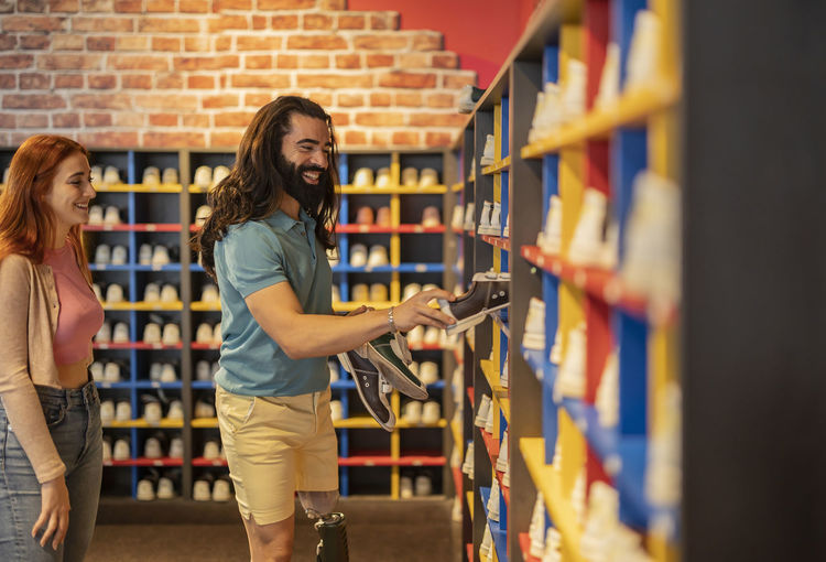 Happy man wearing artificial leg choosing bowling shoe at alley