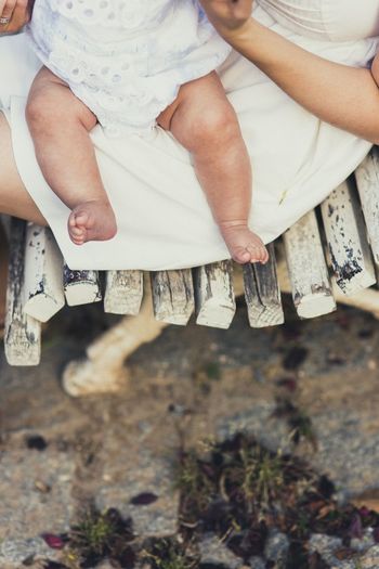 Midsection of mother holding baby while sitting on bench