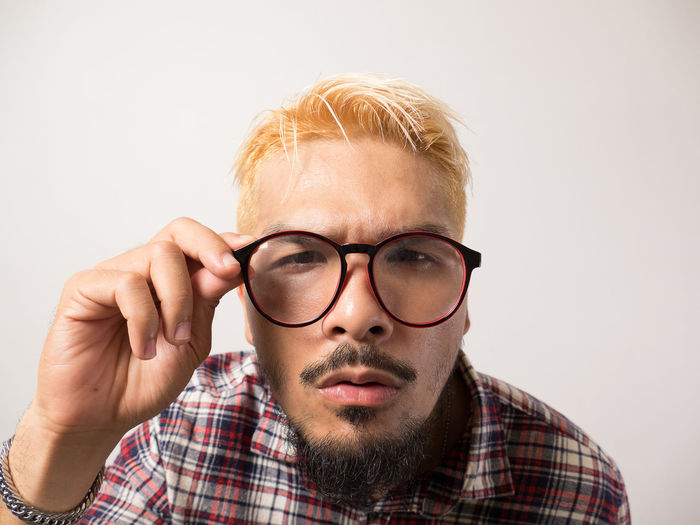 Portrait of man wearing eyeglasses against white background