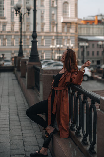 Stylish young brunette woman in fashionable long brown leather coat. autumn street style. casual