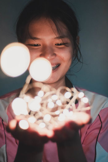 Close-up portrait of woman holding illuminated lamp