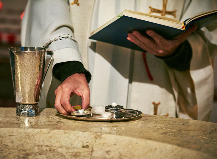 Midsection of priest holding book by plate