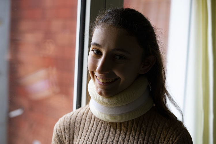 Young woman with a cervical collar smiling.