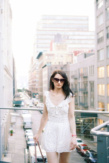 Young woman wearing sunglasses while standing in city