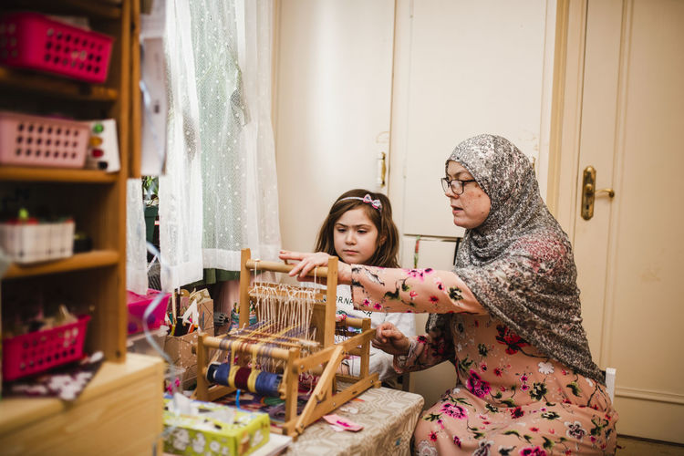 Mother with daughter using loom