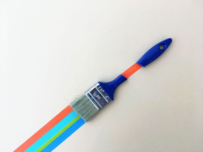 Directly above shot of broken paintbrush arranged on colorful duct tape on white background