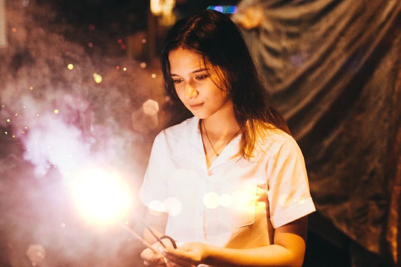 Young woman looking at lit sparklers