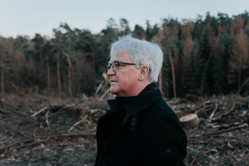 Portrait of man standing on field in forest