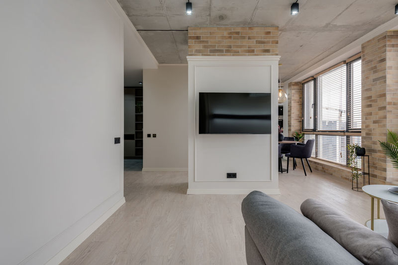 Interior in a modern style and a view of the tv and part of the kitchen near the large windows 