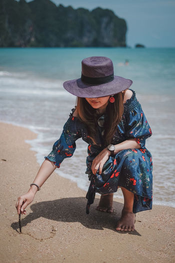 Woman carving on sand at beach