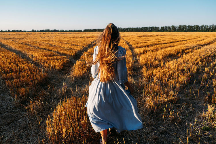 Woman in blue linen dress enjoying nature in sunset field. stress and psychological resilience