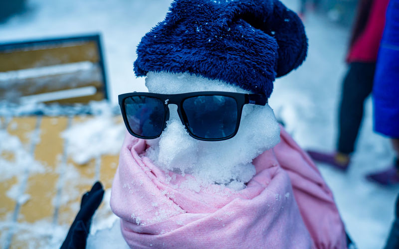 Close-up of snowman with sunglasses and knit hat