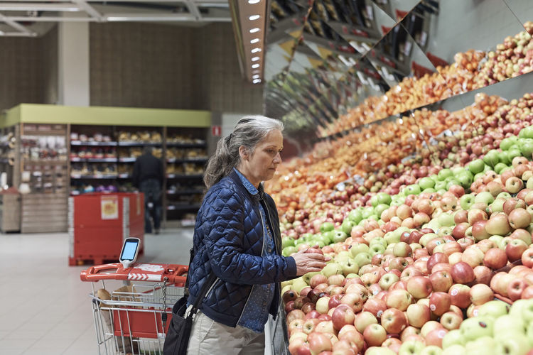 Mature woman buying apples at supermarket