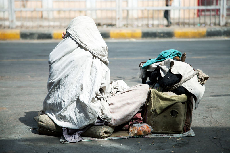 Rear view of beggar begging on street