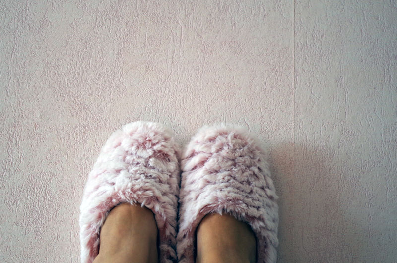 Low section of person wearing slippers on floor