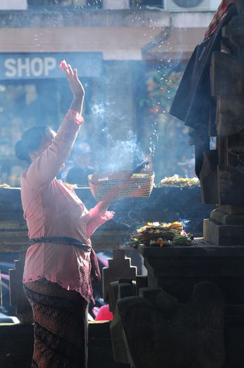 Side view of woman praying at temple