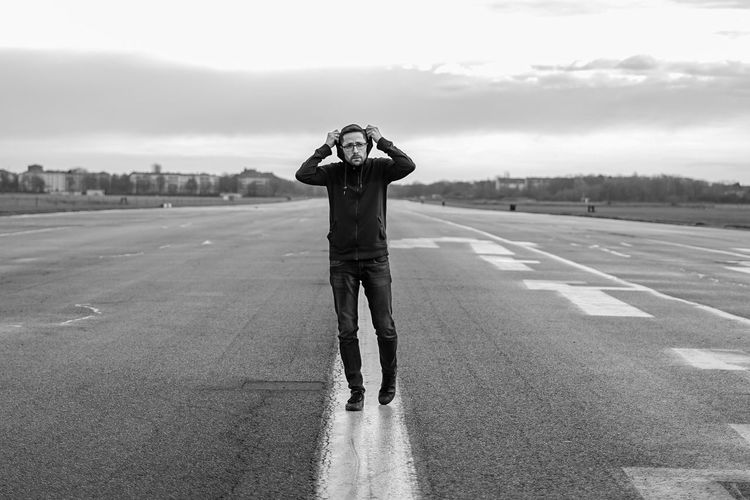 Man wearing hoodie standing on runway against sky