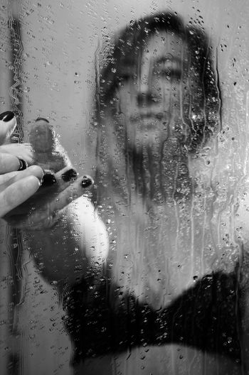 Reflection of woman on wet glass window in rainy season