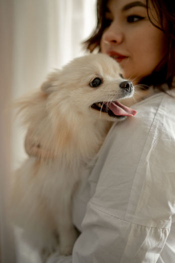 Beautiful young woman with pomeranian dog at home