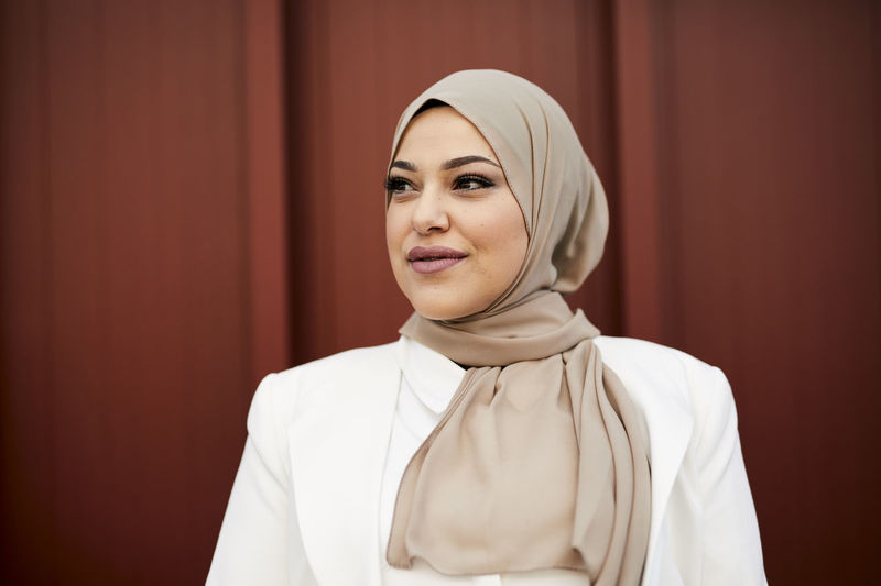 portrait of young woman wearing hijab against yellow wall