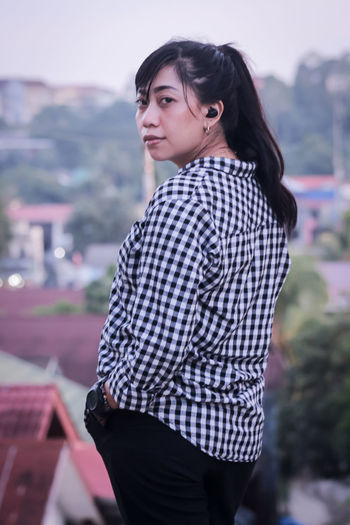 Portrait of young woman standing against trees