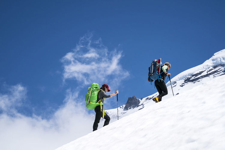 Two female mountaineers hike above cloudline on mt. baker, wa