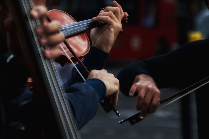Cropped image of men playing violins on street