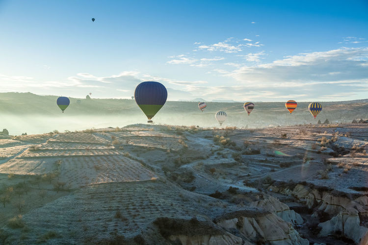 Hot air balloons flying over cappadocia against sky