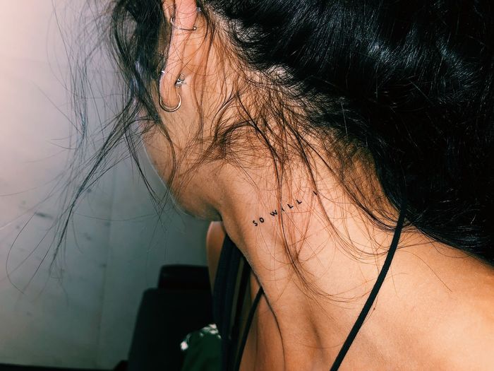 Woman showing text tattoo on her neck