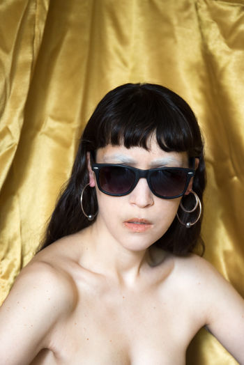Portrait of shirtless woman wearing sunglasses