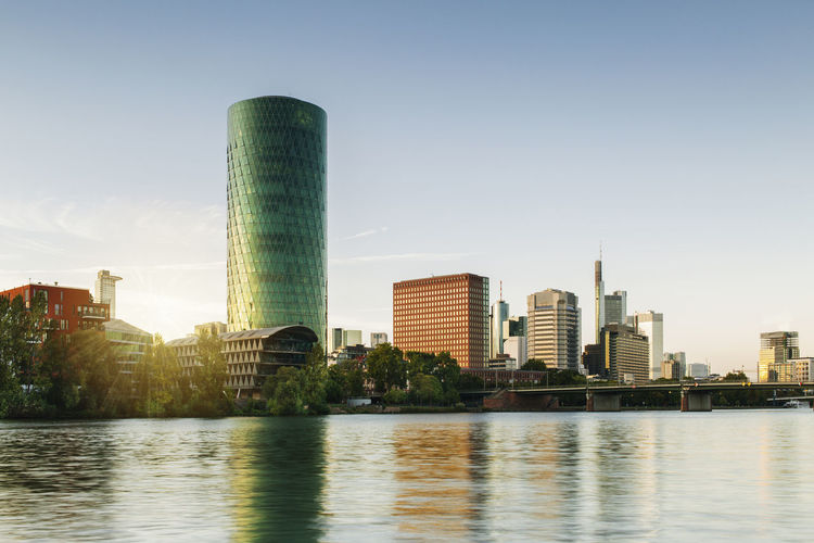 River by modern buildings against sky in city
