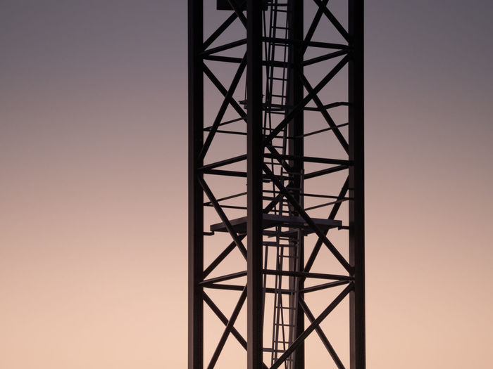 Low angle view of silhouette of metal tower against sky during sunset