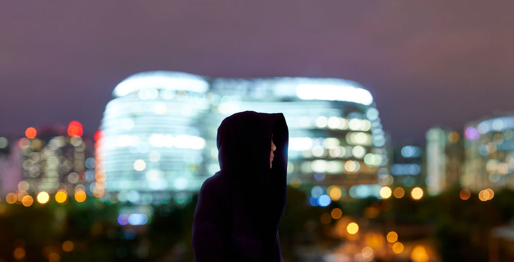 Man standing against illuminated city at night