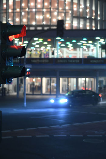 Vertical shot of german stoplight which shows red. blurred lights in the background.
