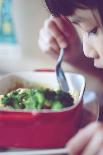 Close-up of girl eating food from container at home