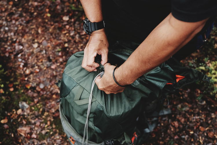 Low section of man with luggage in forest during autumn