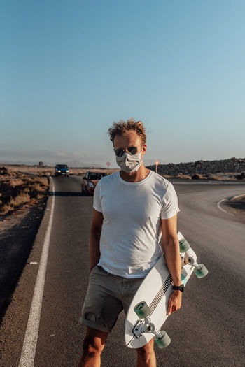 Portrait of man standing on road against clear sky
