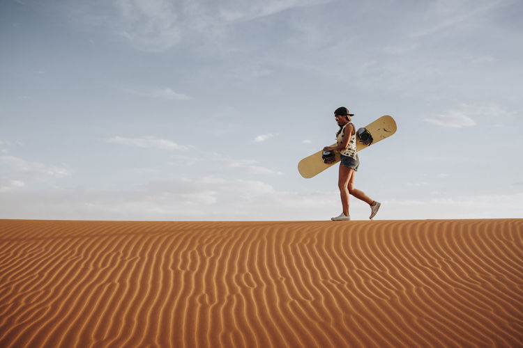 rear view of man jumping on sand at desert