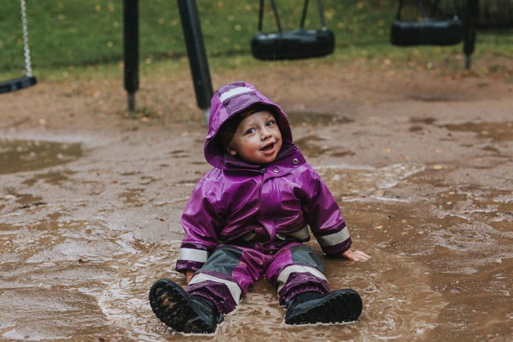 Toddler girl sitting in puddle