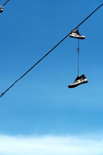 Low angle view of shoes against clear blue sky