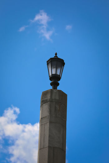 Low angle view of street light by building against sky