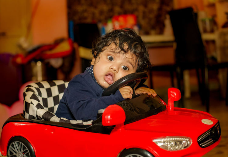 Baby boy posing on his toy car