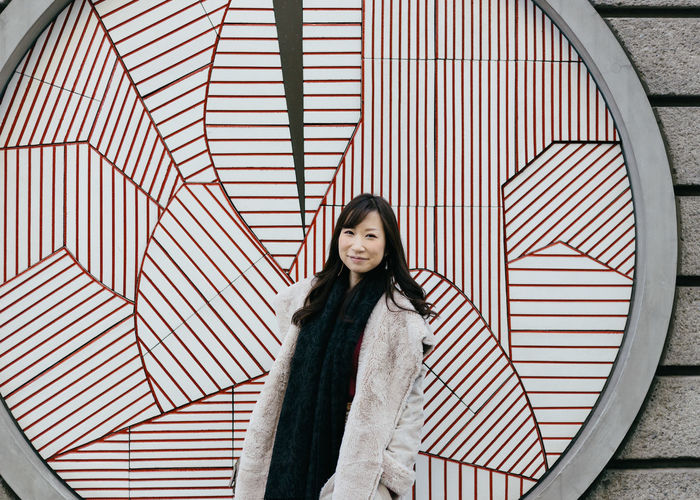 Portrait of young woman standing against patterned wall