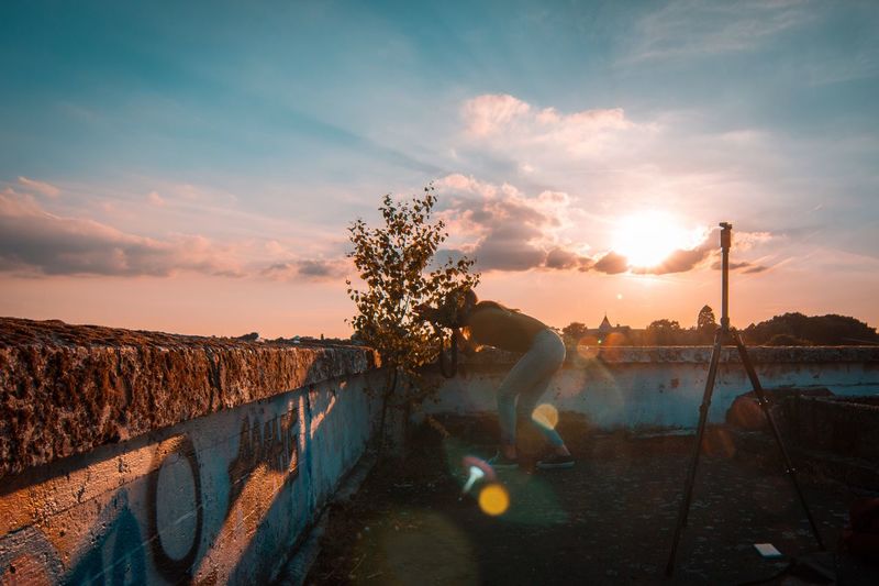 Woman photographing through camera during sunset